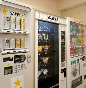 Automater märkta med ”Sapporo”, ”Snacks” och ”Cans Shop”, där det finns olika sorters drycker och snacks.