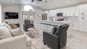 Une cuisine moderne avec des meubles blancs, un îlot central et des luminaires suspendus.