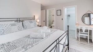 Une chambre à coucher avec un lit, un bureau, un miroir et un ventilateur de plafond.