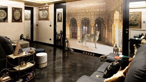 A room with a large mural of a leopard, a sofa, a small table with decorative items, and a door with intricate designs. - Dubai RC luxury (Reggio Calabria)