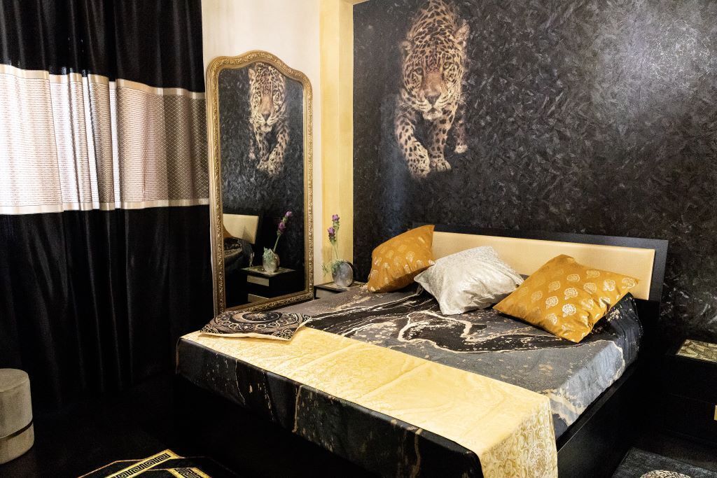 A bedroom with a large bed, a mirror, and a leopard print wall.