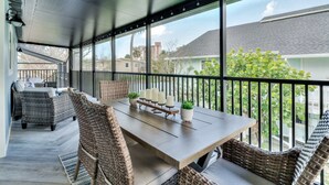 A covered outdoor patio with wicker furniture, a table, and candles. - Island Gold Steps to the Beach - Heated Pool (Fort Myers Beach)