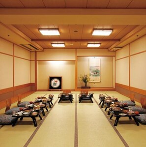 Une pièce de style japonais traditionnel, avec des tatamis, de petites tables basses et des coussins.