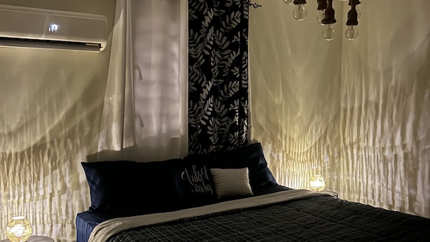 Ett sovrum med en säng, ett sängbord, en lampa och en taklampa.