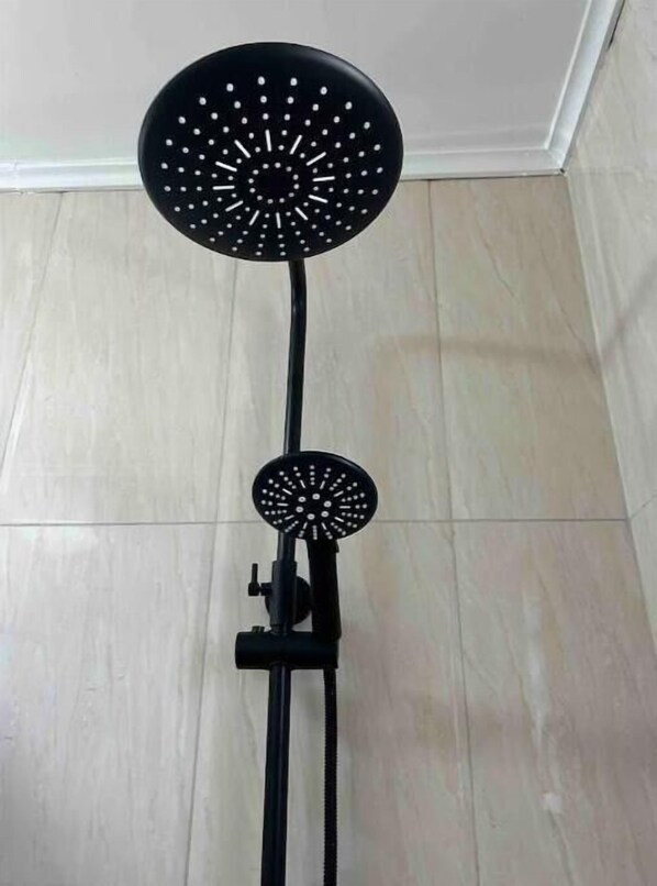 Une pomme de douche noire, portable, montée sur un support.