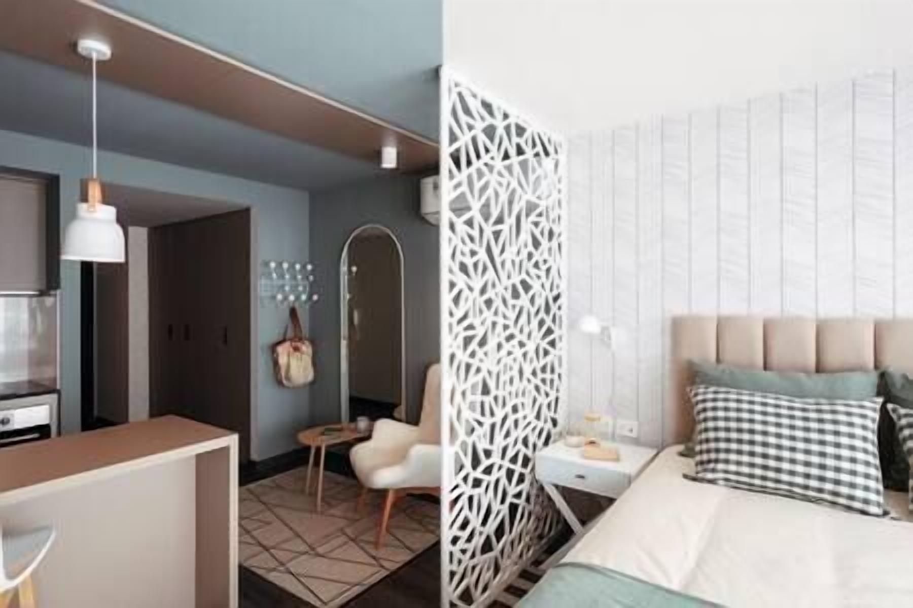 A modern hotel room with a bed, bedside table, and a decorative white partition.