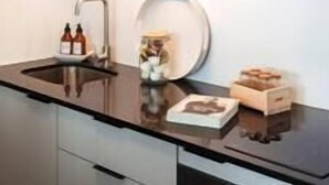 Een moderne keuken met een donker aanrecht, roestvrijstalen apparatuur en een minimalistisch design.