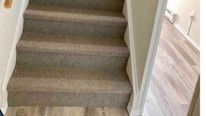 A carpeted staircase with wooden handrails, leading to a room with a light-colored floor. - Comfy and modern private suite - everything you need for a short to midterm stay (Dryden)