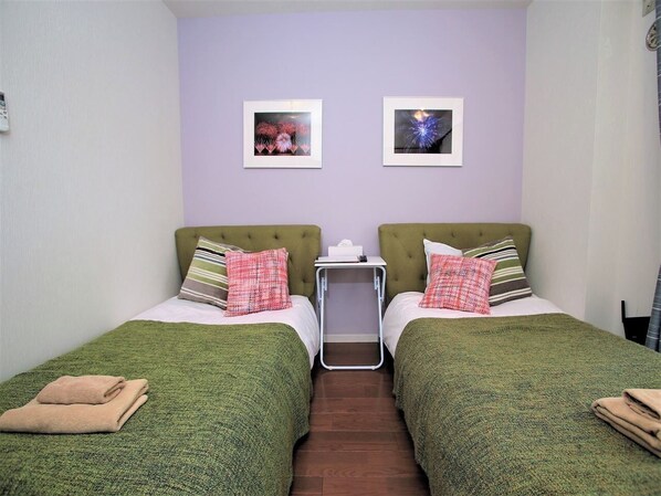 A twin room with two beds, each with green bedding and matching pillows, a small bedside table with a tissue box, and two framed pictures on the wall. - Standard Twin201 / Ota-ku Tokyo (Ota-ku)