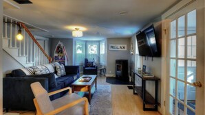 Een gezellige woonkamer met een bank, fauteuil en een open haard.