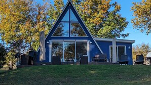 A modern house with a triangular roof, large glass windows, and a patio with outdoor furniture.