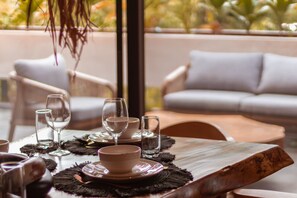 Een eettafel gedekt met borden, kommen en glazen, met uitzicht op een balkon en terras.