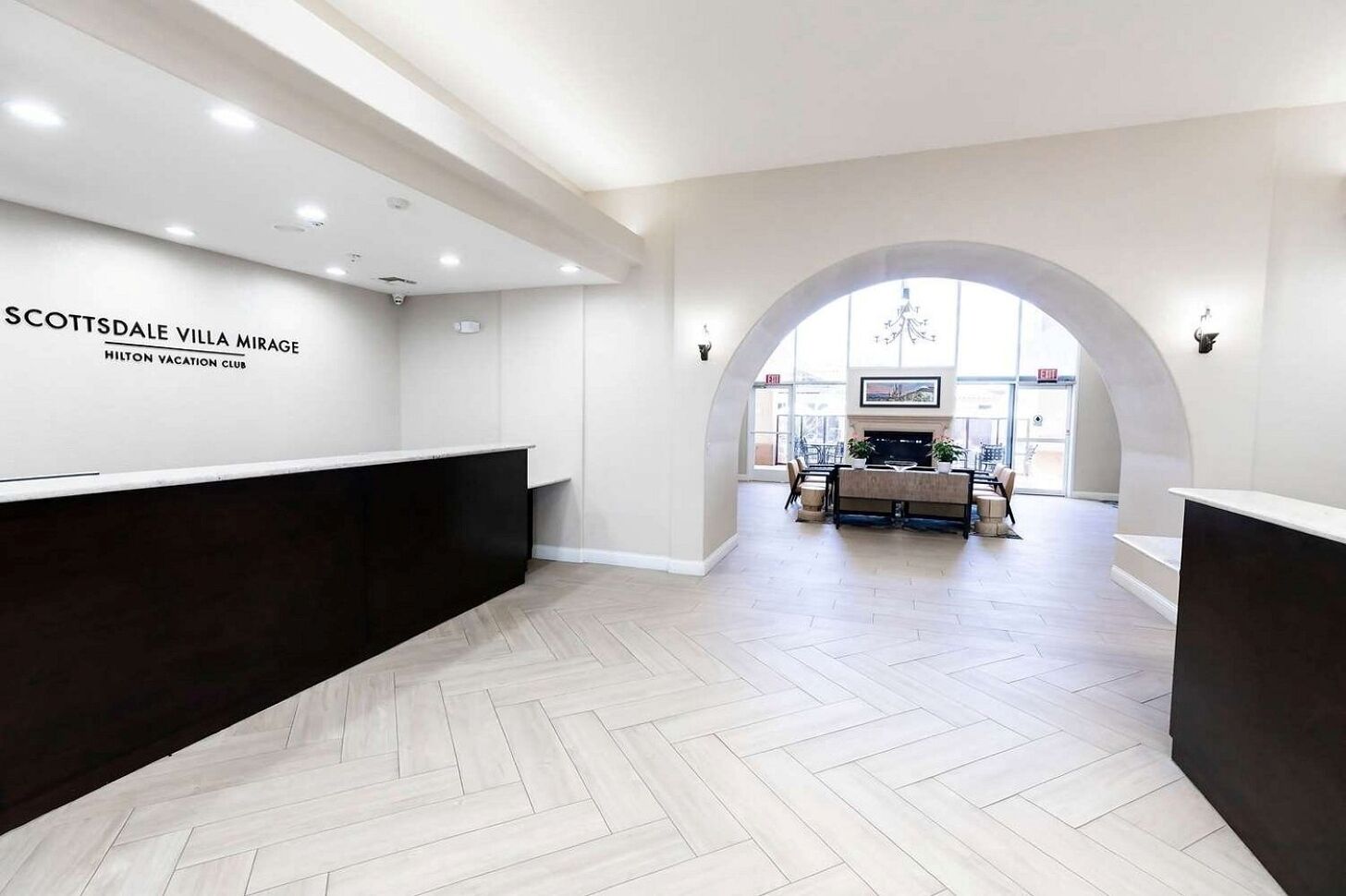 A reception area with a herringbone floor, a reception desk, and a seating area with a fireplace.