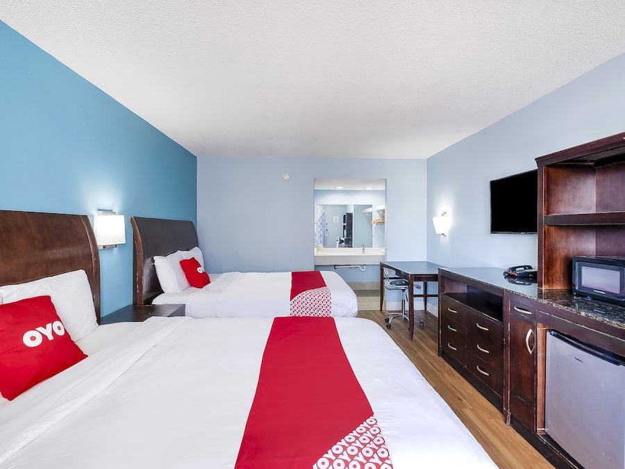 Habitación de hotel con dos camas, un escritorio, un microondas y un refrigerador.