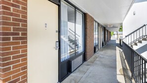 Um corredor com parede de tijolos, uma porta com a inscrição '101' e uma escada com o sinal 'EXIT'.