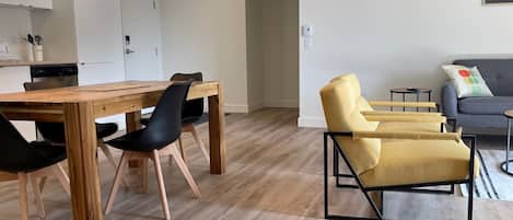 Un salón moderno con una mesa de comedor de madera, sillas negras y un sillón amarillo.