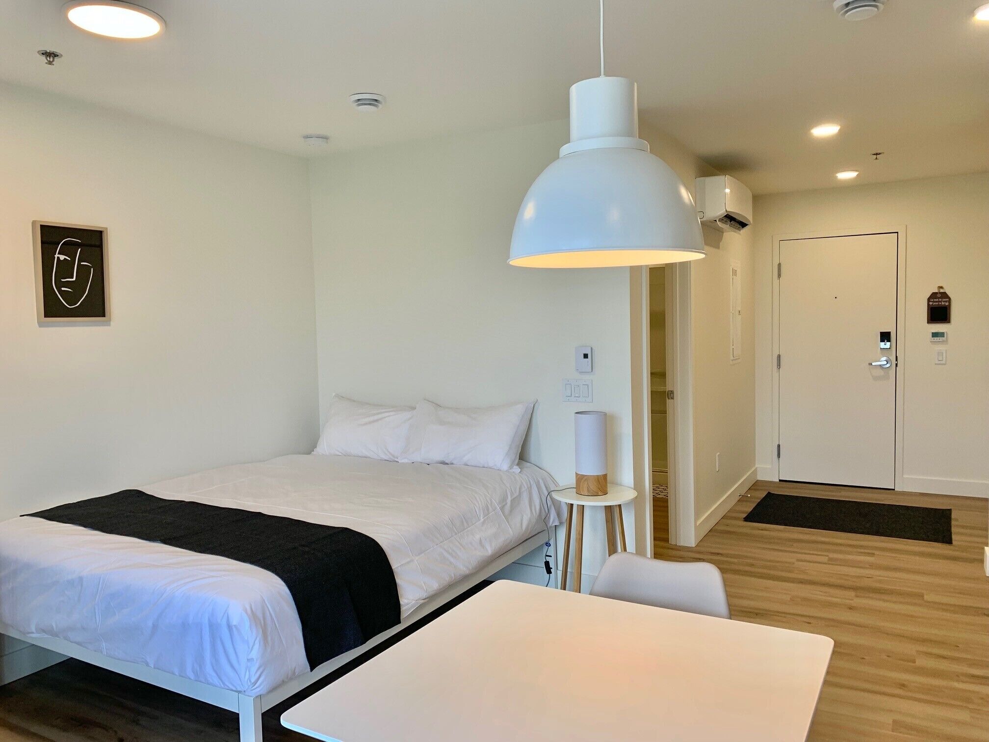 Una habitación de hotel moderna con una cama, mesita de noche y una lámpara colgante.