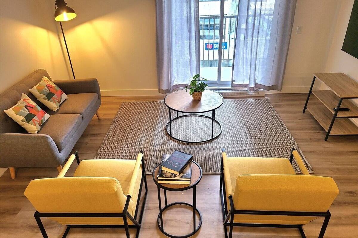 A living room with a sofa, two yellow armchairs, a coffee table, and a floor lamp.