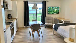 A modern hotel room with a kitchenette, a dining area, a bed, and a TV. - Appart-Hôtel L'UNI (Québec City)