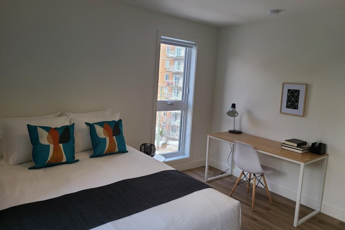 A bedroom with a large bed, a desk, and a chair.