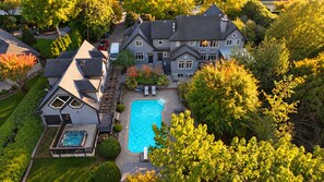 A large house with a swimming pool, a hot tub, and a deck area.