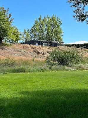 Een modern gebouw met een plat dak, omgeven door een grasveld en bomen.