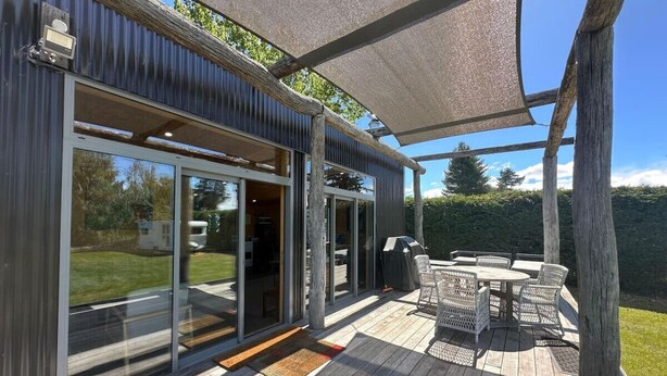 A deck with outdoor furniture, a grill, and a pergola providing shade. - The River Cabin, Twizel. (Twizel)