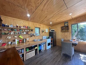 A compact kitchen with wooden walls, a built-in microwave, and a window overlooking greenery.