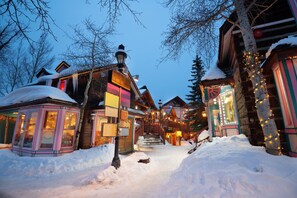 A snow-covered street with wooden buildings, a staircase, and a snow-covered roof. - SKI-IN Condo in Breckenridge (Breckenridge)