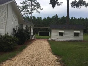 A gravel driveway leading to a house with a covered porch and a small shed. - Quiet Wilcox County Retreat-Long Leaf Pine Lodge (Rochelle)