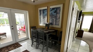 A dining area with a table and chairs, a ceiling fan, and a view of the outside patio.