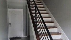 A staircase with a metal railing, wooden steps, and a white door at the bottom.