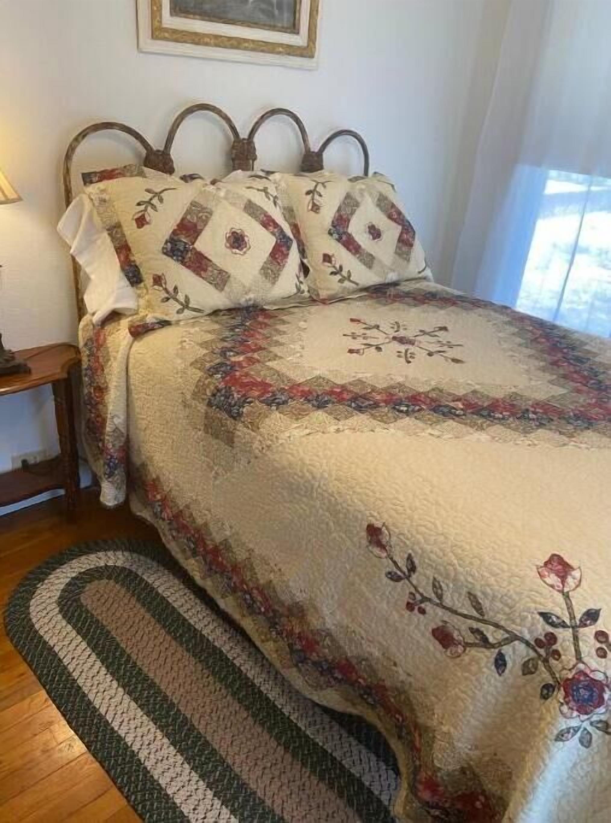 Een bed met een quilt met bloemenprint, een houten hoofdbord en een bijpassend kussen.