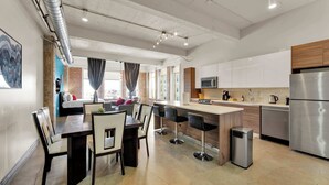 A modern kitchen with a central island, stainless steel appliances, and a dining area with bar stools.