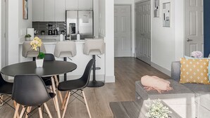 Une cuisine moderne avec des meubles blancs, un réfrigérateur et un coin repas comprenant une table ronde et des chaises.