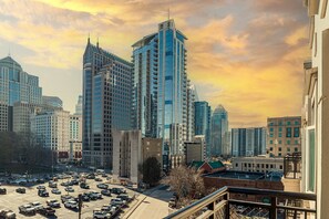 Eine Stadtansicht mit modernen Hochhäusern, einem Parkplatz und einer Mischung aus Geschäfts- und Wohngebäuden.