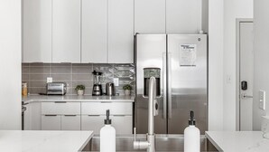 Une cuisine moderne équipée d’appareils électroménagers en acier inoxydable, d’un grille-pain encastré et d’un distributeur d’eau.