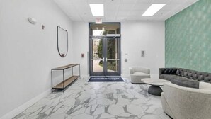 A modern lobby with a marble floor, a sofa, a bench, and a mirror. - Urban Retreat | Free WiFi+Parking, Walk to Stadium (Charlotte)