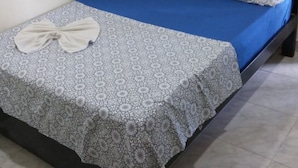 Una cama individual con colchón azul y edredón estampado, almohada blanca y otra a juego en un cabecero oscuro.