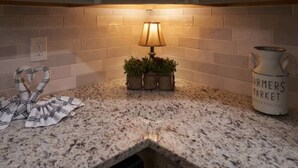 A kitchen counter with a granite top, a small table lamp, a potted plant, a cloth, and a pitcher labeled "Farmers Market". - ENTERTAINMENT GALORE!NEWLY UPGRADED -GREAT LOCATION, CLOSE TO MAJOR ATTRACTIONS! (Sevierville)