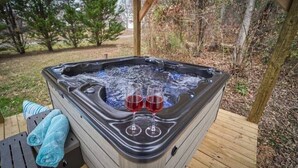 A hot tub with two glasses of red wine, a towel, and a wooden deck. - ENTERTAINMENT GALORE!NEWLY UPGRADED -GREAT LOCATION, CLOSE TO MAJOR ATTRACTIONS! (Sevierville)