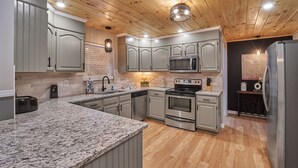 A modern kitchen with granite countertops, stainless steel appliances, and wooden flooring. - ENTERTAINMENT GALORE!NEWLY UPGRADED -GREAT LOCATION, CLOSE TO MAJOR ATTRACTIONS! (Sevierville)