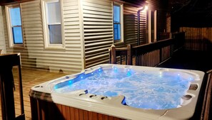 A hot tub on a wooden deck with a house in the background.
