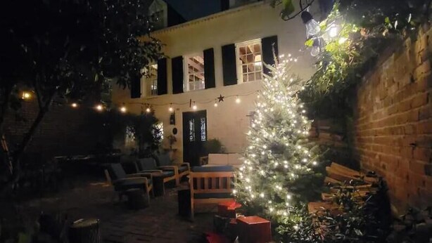 A cozy outdoor seating area with a Christmas tree and string lights. - Washington Family Home - National Treasure, Est 1750 located at 107 S Lee Street (Alexandria)