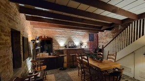 A rustic kitchen with a wooden table and chairs, a bar area, and a staircase with a railing. - Washington Family Home - National Treasure, Est 1750 located at 107 S Lee Street (Alexandria)