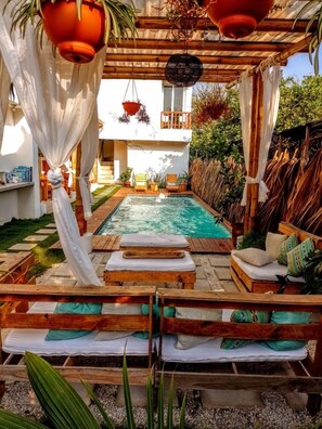 A pool area with wooden loungers and a pergola overhead. - Wander Boutique Hotel (Sipacate)