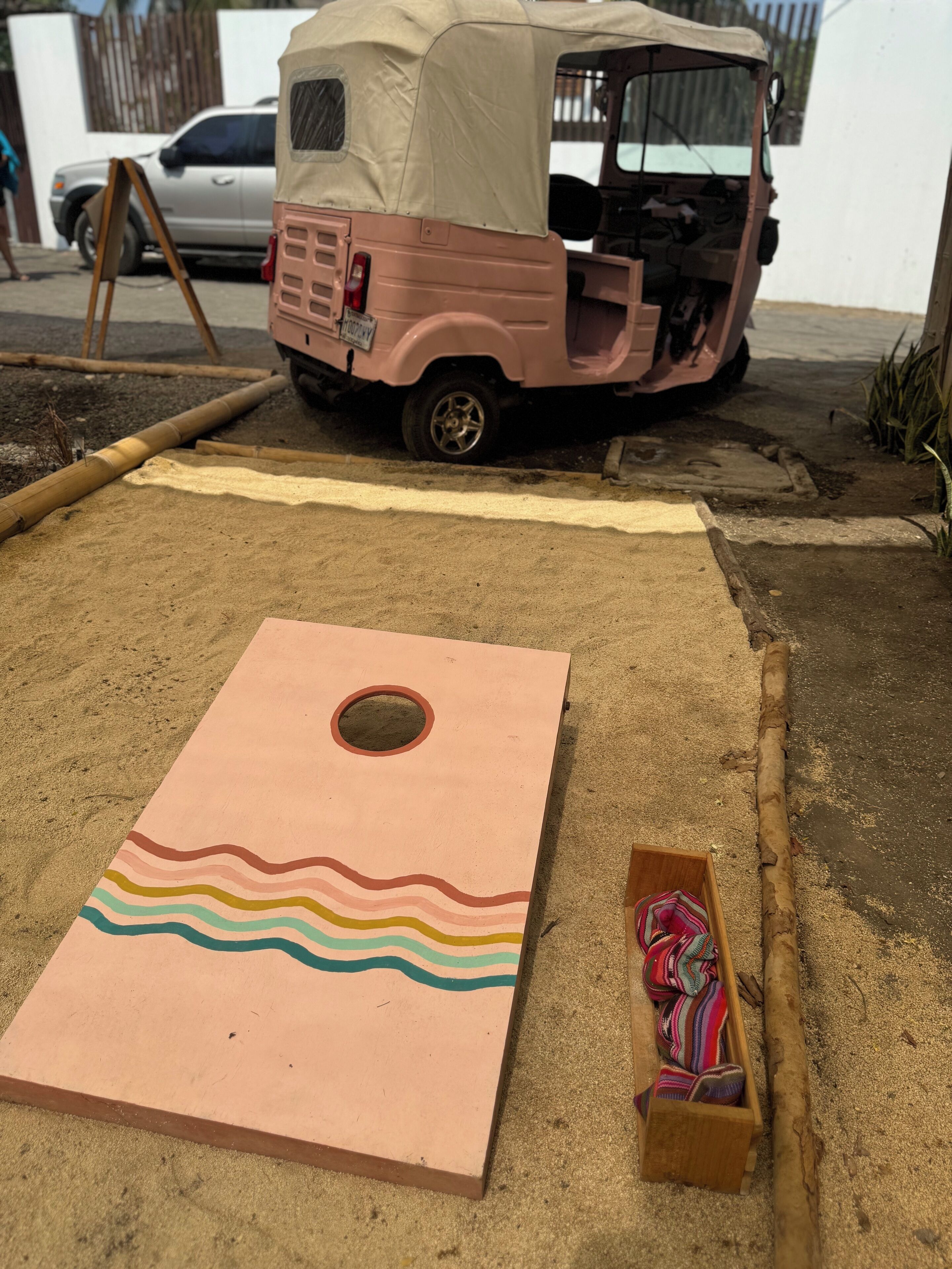 Una bressolera amb un tauler colorit, una petita caixa de fusta, i un vehicle rosa al fons.