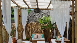 A covered outdoor seating area with wooden furniture and white canopies.