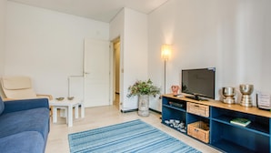 A living room with a sofa, a TV, a small table, and a decorative plant. - 2 bedroom awesome apartment in Moneglia (Moneglia)