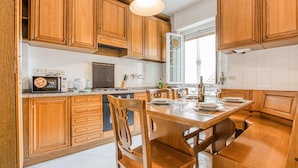 A kitchen with wooden cabinets, a dining table set for four, and a window with a view. - 2 bedroom awesome apartment in Moneglia (Moneglia)